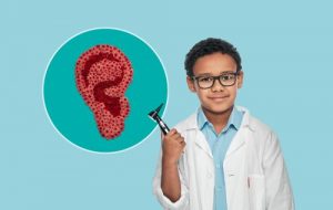 a child dressed as an audiologist with a digital image of an ear next to him